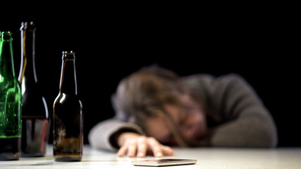 Female suffering alcohol poisoning sleeping near phone on table, medical care