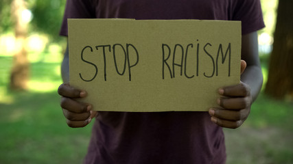 Afro-american male showing stop racism phrase cardboard, equal rights, abuse