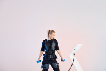 healthy girl checking the ems machine during the workout with dumbbells. close up photo.isolated white background. - obrazy, fototapety, plakaty