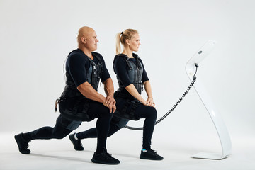 fit man and woman stretching legs indoors doing forward lunge. full length side view photo. young...