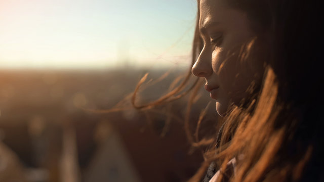 Lonely pensive young lady standing on skydeck, upset wit personal troubles