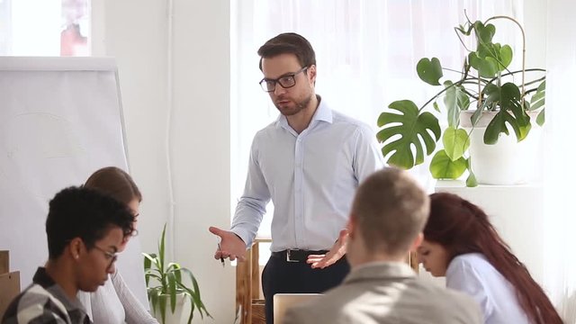 Angry boss shouting at group office meeting scolding criticizing employees