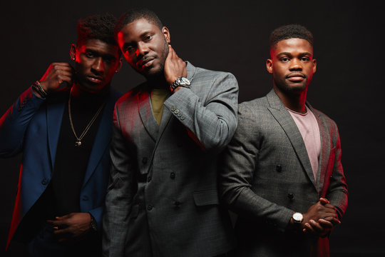 Group of three african friends dressed in stylish suits posing isolated in studio over dark background. Classmates have grown up and become successful people. People, Fashion condept