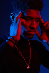 Low key studio shot of serious concentrated young African business man, holding fingers on temples and looking inside himself as if trying to remember something important