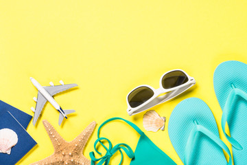 Blue flip flops, swimsuit, sunglasses and starfish on yellow background.