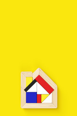 3D rendering illustration of house-shaped puzzle placed in the lower center of vertical format. Yellow background with copy space, flat layout.