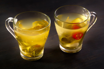 Two glass cups with cucumber pickle on a wooden board. Close-up
