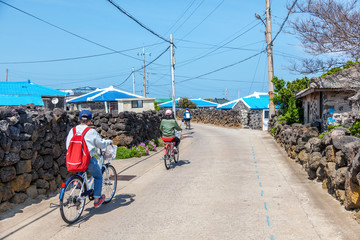 Tourists ride a bicycle along a street on Udo Island, a trip to South Korea