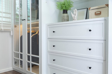 Dark handle on the white facade of the cabinet.