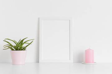 White frame mockup with a succulent plant and a candle on a white table. Portrait orientation.