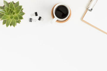 Workspace accessories, coffee and a succulent plant on a white table.  Flat lay with blank copy space.