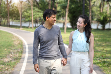 asian couple walking and talking in the park with happy face