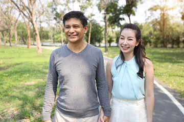 Fototapeta premium asian couple walking and talking in the park with happy face