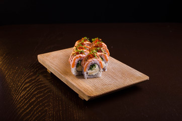 Beautiful sushi rolls with tuna on a wooden plank. Japanese sushi with fish in the Ukrainian seafood restaurant. Menu rolls on a black background
