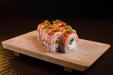 Beautiful sushi rolls with tuna on a wooden plank. Japanese sushi with fish in the Ukrainian seafood restaurant. Menu rolls on a black background
