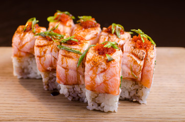 Beautiful sushi rolls with tuna on a wooden plank. Japanese sushi with fish in the Ukrainian seafood restaurant. Menu rolls on a black background