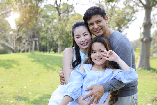 image of happy family, daughter showing victory symbol on her hands with smiling during summer time in the park