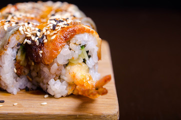 Menu of Ukrainian seafood restaurant. Japanese sushi rolls. Sushi set maki with shrimp,  tuna, eel and avocado. Dish on a wooden plate sprinkled with sesame