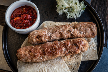 Two lula kebabs on pita bread with onions and red tomato sauce