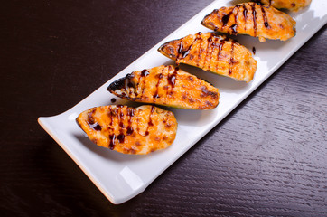 Menu of Ukrainian seafood restaurant. Baked mussels with garlic and cheese. Poured with sauce and sprinkled with sesame. Tasty lunch