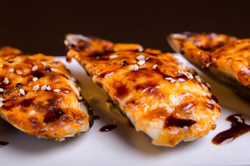 Menu of Ukrainian seafood restaurant. Baked mussels with garlic and cheese. Poured with sauce and sprinkled with sesame. Tasty lunch