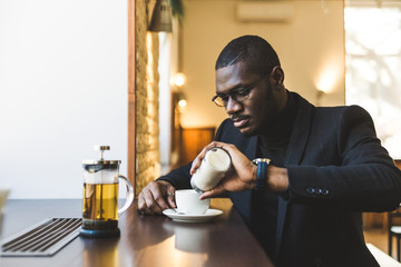 Young handsome dark-skinned businessman in a cafe with a cup of tea.