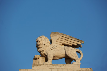 Fototapeta premium statue of lev against the sky and under his paw book