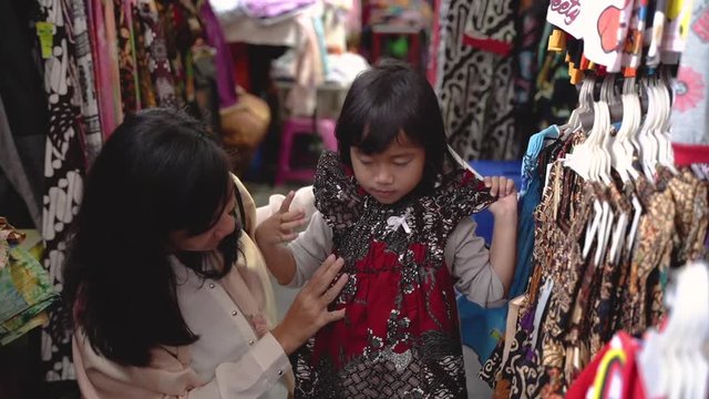indonesian mother buy and try batik for her daughter in tradtional market