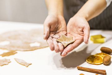 Young pretty woman prepares the dough and bakes gingerbread and cookies in the kitchen. She holds a star cut from the dough in her hands. Merry Christmas and Happy New Year.