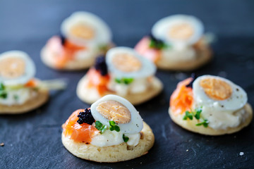 Party food, blinis with salmon, quail egg and caviar