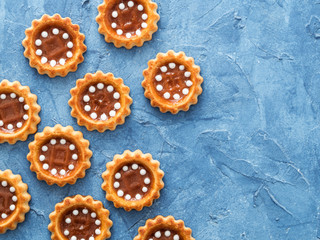Cookies with caramel on blue textured concrete background. Top view or flat lay. Food background with copy space