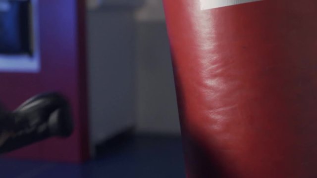 Close up, kick on a punching bag with boxing glove, slow motion boxer training