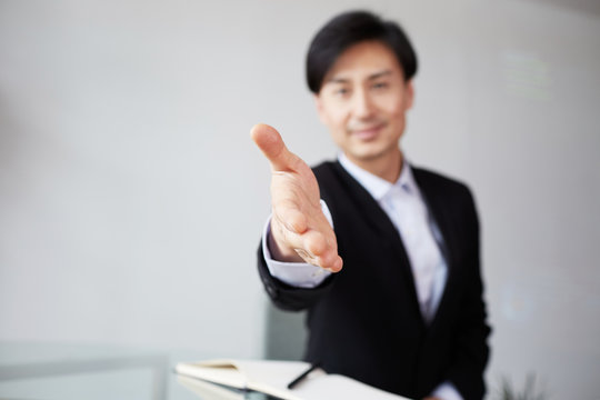 Confident Young Asian Businessman Offering Handshake After Business Deal