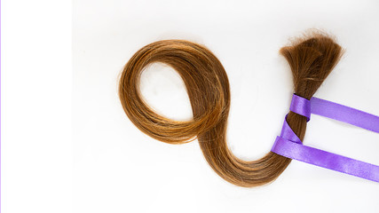 long blond hair donationwith lavender ribbon as symbol of fight against cancer on white background. Top view. Natural material for making wig for patients. Horizontal with copy space, isolated Concept