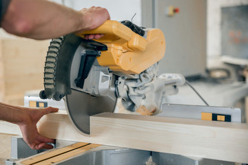 Worker cuts a wooden beam circular saw.