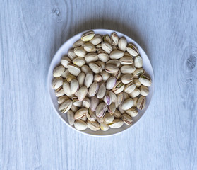 Healthy food  for background image close up pistachios nuts. Texture on white grey table top view. Nuts pistachio on the cup plate