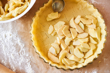 Home baking of holidays classic sweet pies. Woman hands fixing pastry dough in a tray and pumpkin...