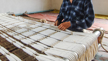 weaving and manufacturing of handmade carpets close-up. man's hands behind a loom