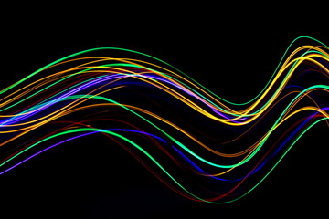 Long exposure, light painting photography.  Vibrant multicolor streaks of neon color against a black background.