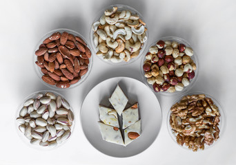 Oriental dessert halva with pistachio, almond, cashew nuts, peanut, walnut  on a  plate. Image. Healthy food. closeup of sweets from Iran popular  Turkish Delight. Isolated on background