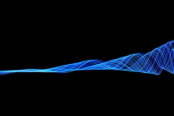 Long exposure, light painting photography.  Abstract waves of neon electric blue color against a black background.