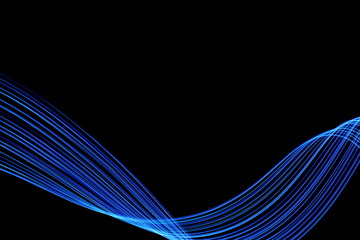 Long exposure, light painting photography.  Vibrant abstract streaks of electric blue color against a black background.