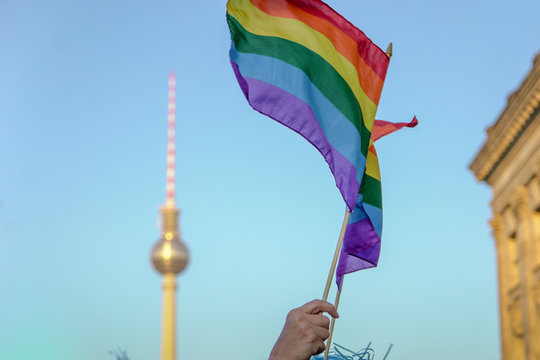 LOW ANGLE VIEW OF HAND HOLDING RAINBOW FLAG DURING CSD-PARADE IN BERLIN