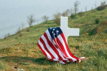 The grave of a soldier. American flag over the grave of the deceased soldier. At the grave a military cap