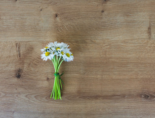 Top view of a bunch or bouquet of blooming white daisies on a wooden background. Hello spring or floral spring background