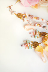 golden  jewerly braslete and earning with semiprecious and roses petals at white background