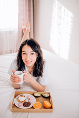 Young woman eating healthy breakfast in bed