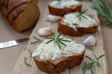 Sliced bread with light cheese on a wooden board.
