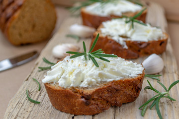 Sliced bread with light cheese on a wooden board.