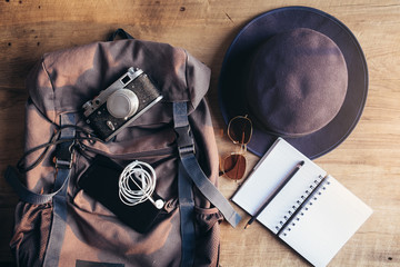 Travel accessories set on wooden background:phone,passport shoes, cap, bag leather, map, camera and sunglasses. Top view point